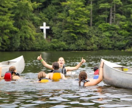 Staff and campers swimming by canoes on the Rock Climbing & Canoeing Pioneer Expedition