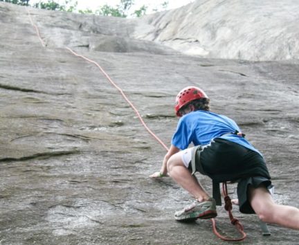 Boy climbing a rock wall on the Rock Climbing & Canoeing Pioneer Expedition