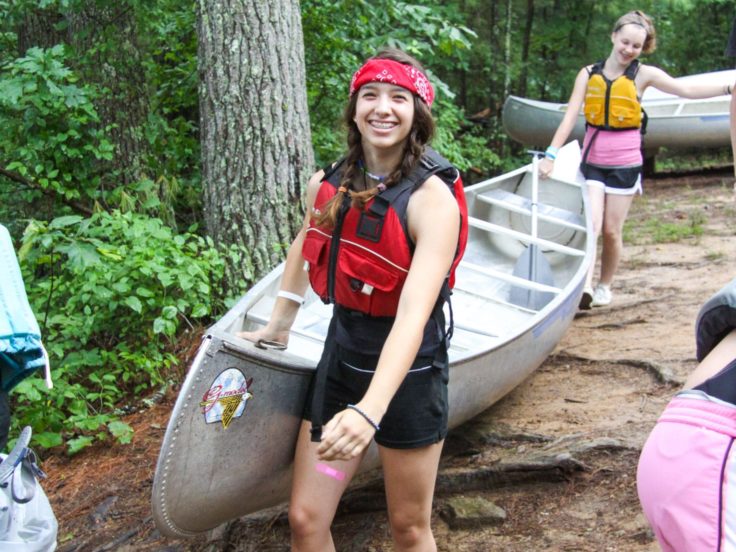 Two female campers carrying a canoe on the Rock Climbing & Canoeing Pioneer Expedition