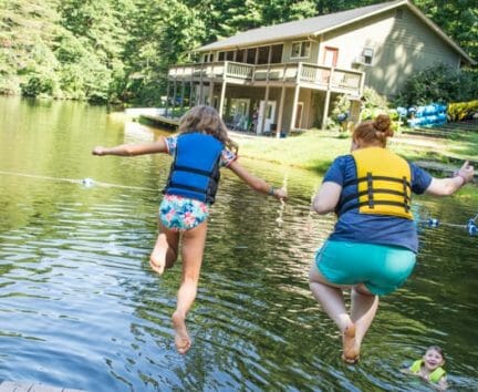 Staff and camper jumping off dock