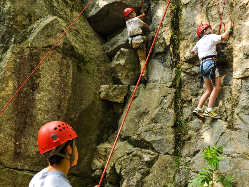 Two young male climbers on an outdoor rock wall on the Rock Climbing & Canoeing Pioneer Expedition
