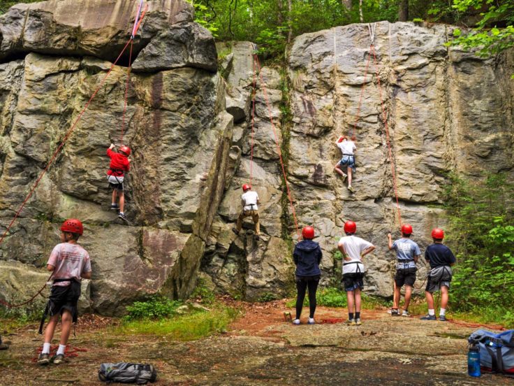 Group of teens climbing a rock wall on the Rock Climbing & Canoeing Pioneer Expedition